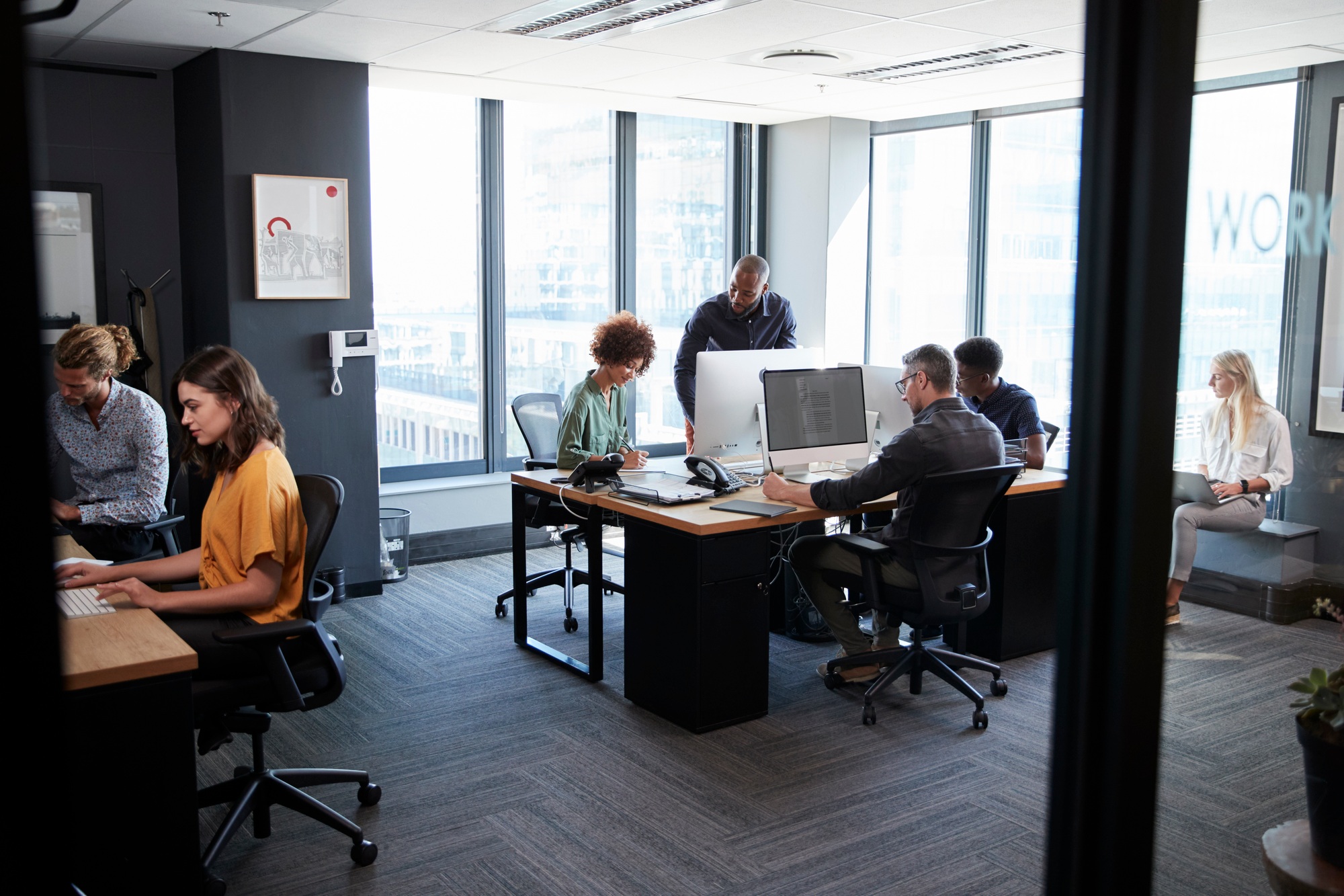 young-creative-team-working-together-at-computers-in-a-casual-office-seen-from-doorway